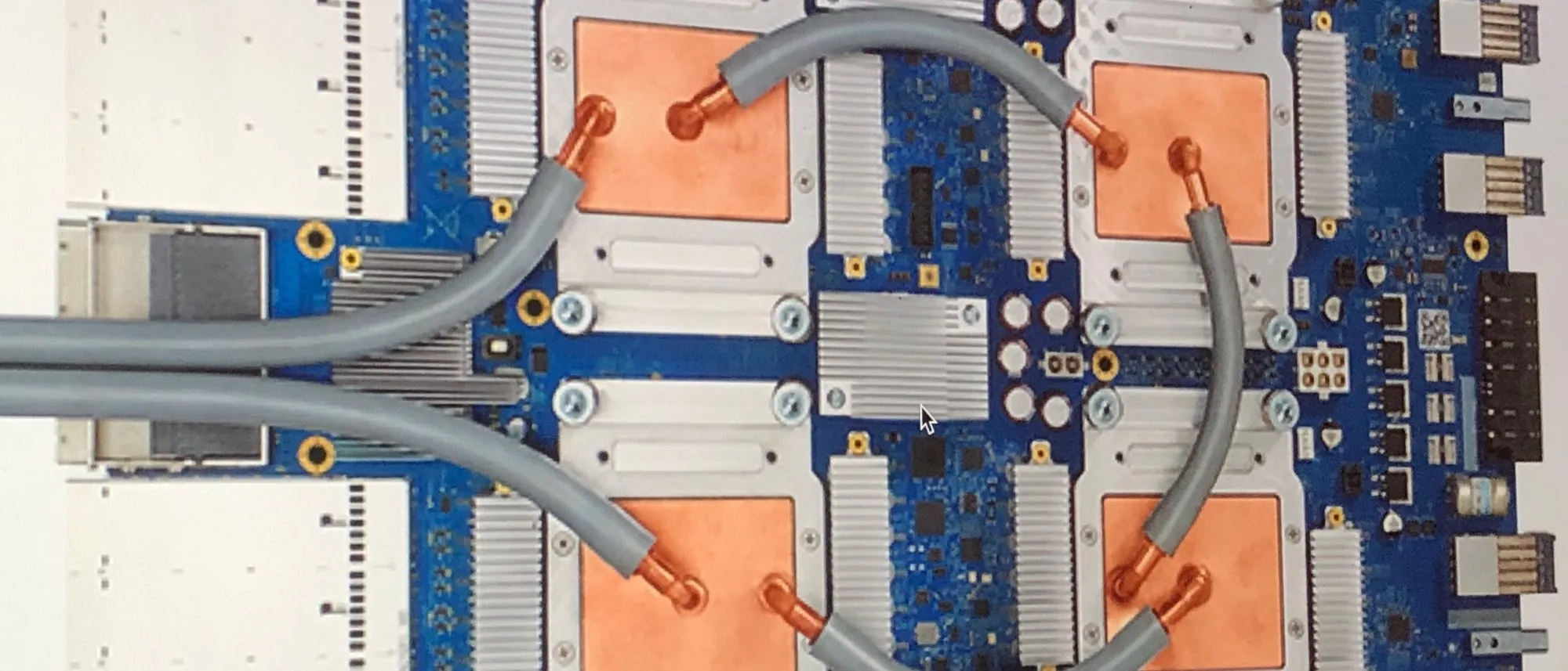 A Google Tensor Processing Unit 3.0 board: four copper-capped chips joined by grey cooling tubes on a blue circuit board