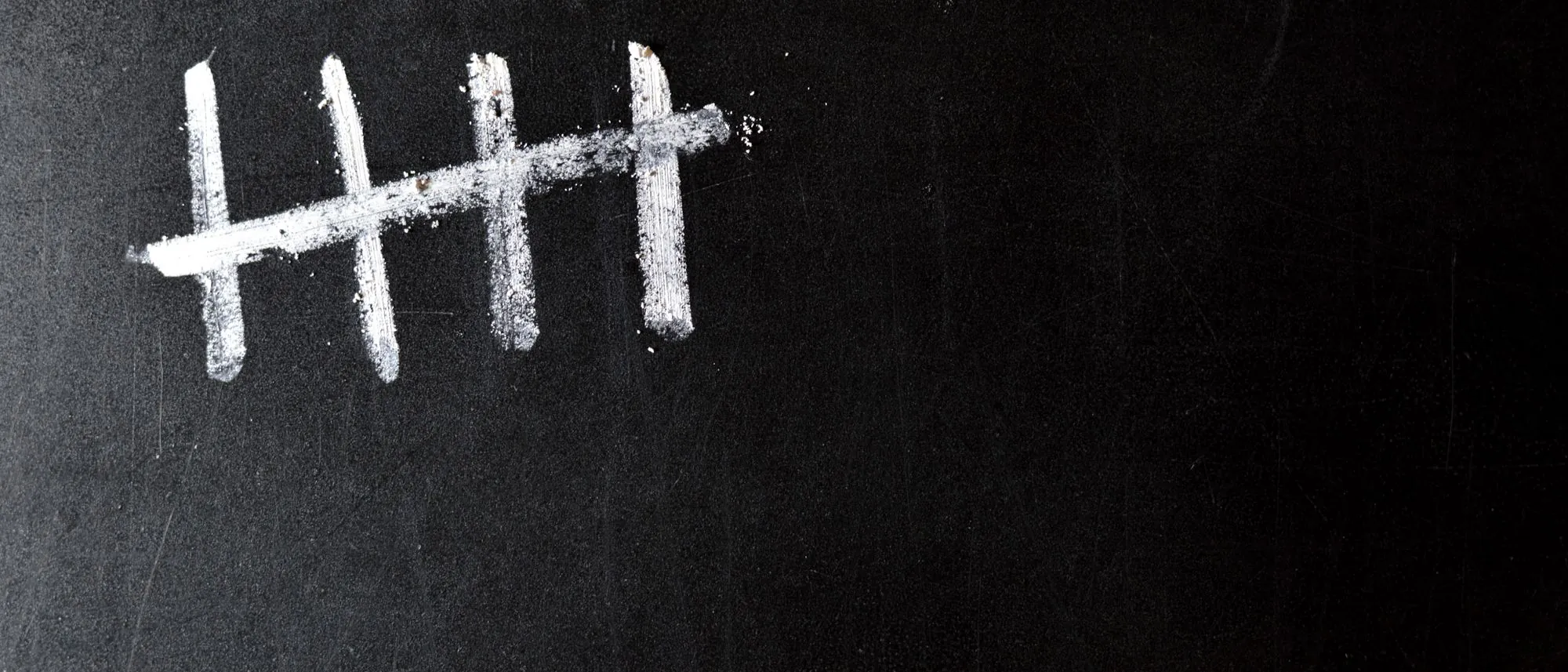 Five chalk tally marks on a black chalkboard