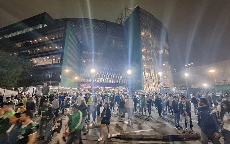 The glass facade of the Nubank Parque stadium in São Paulo lit at night with crowds outside