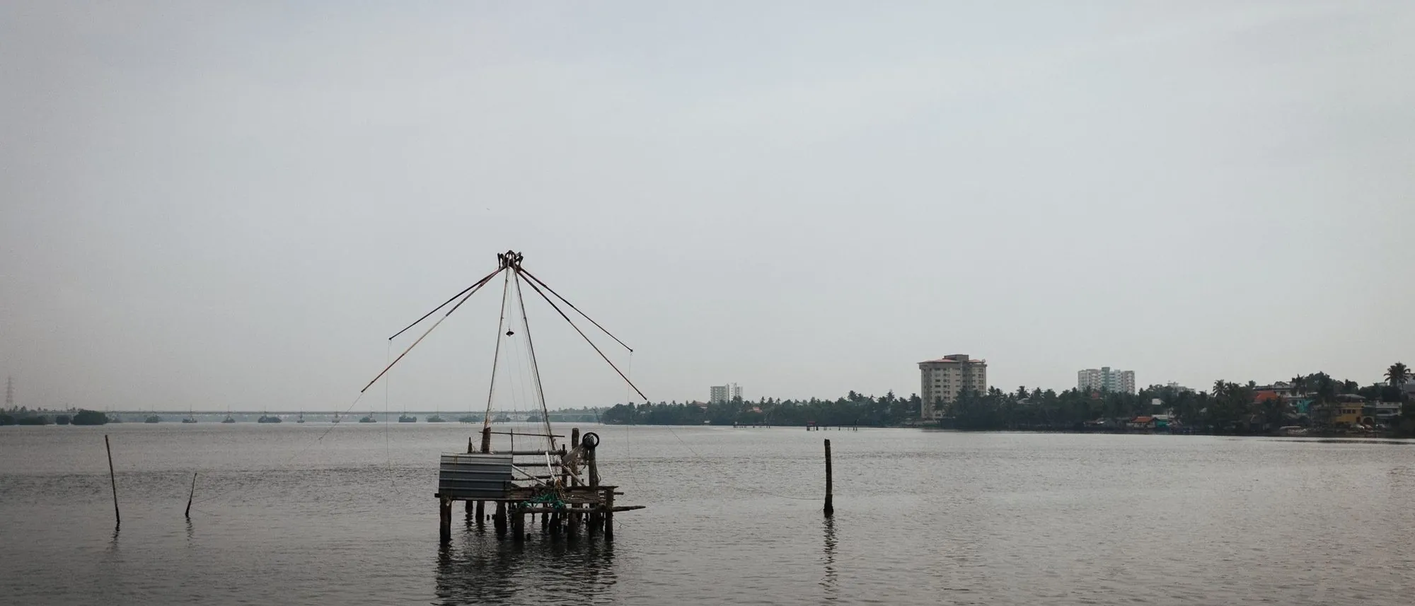A shore-operated lift net hangs over the water on the Kochi coastline.