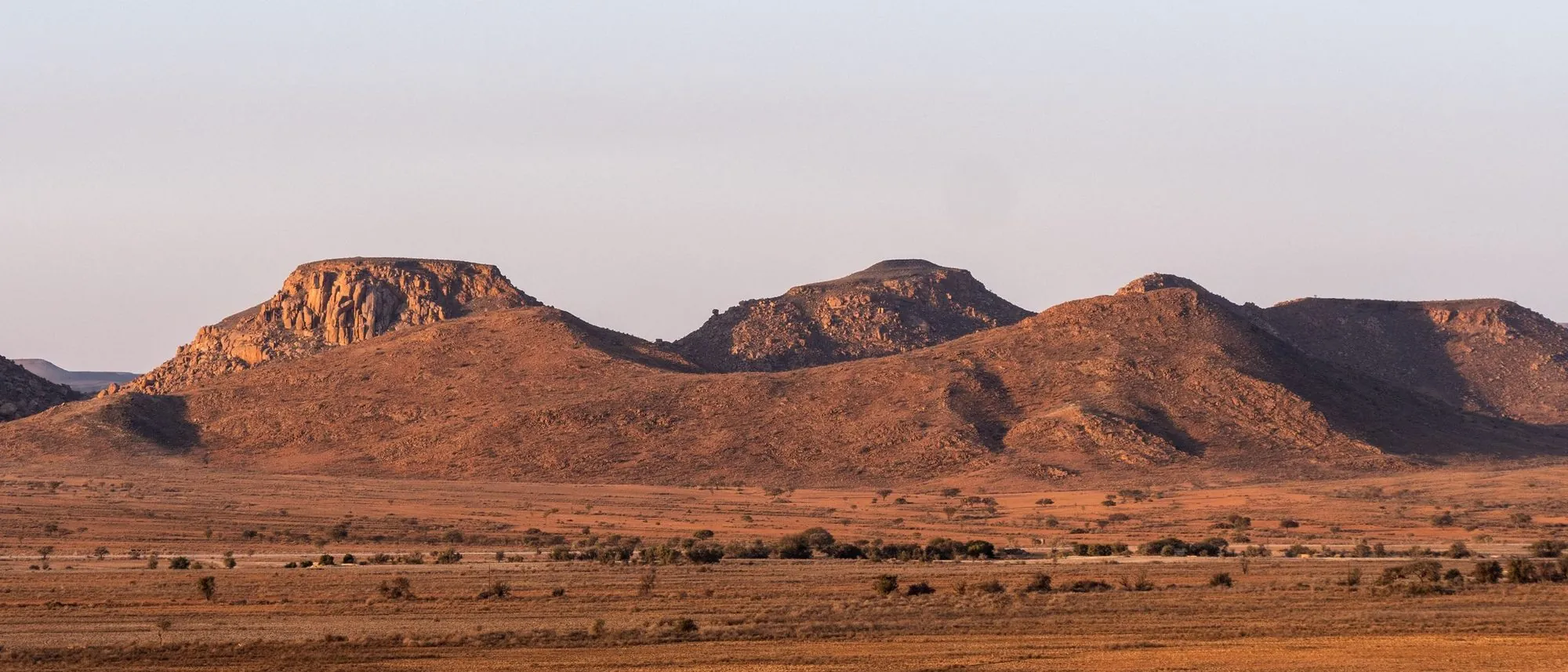 Flat-topped rocky plateaus stretch to the horizon under a sunset sky in South Africa.