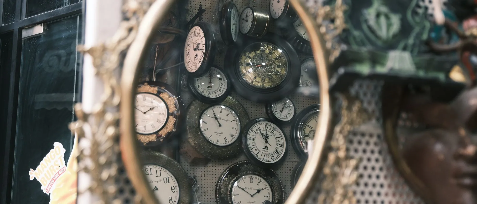 A collection of vintage clocks reflected in an ornate antique mirror in Bengaluru.