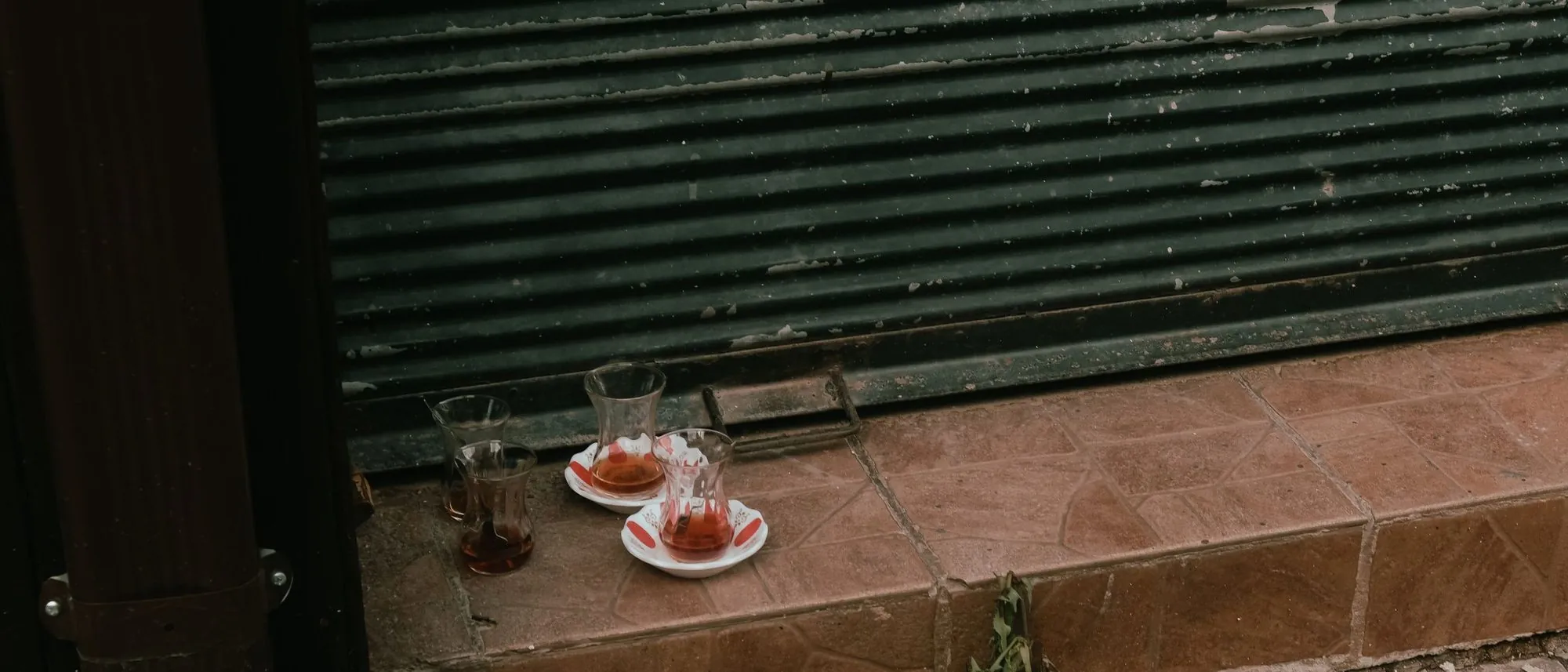 Empty tea glasses left behind on a stone step in a city street.