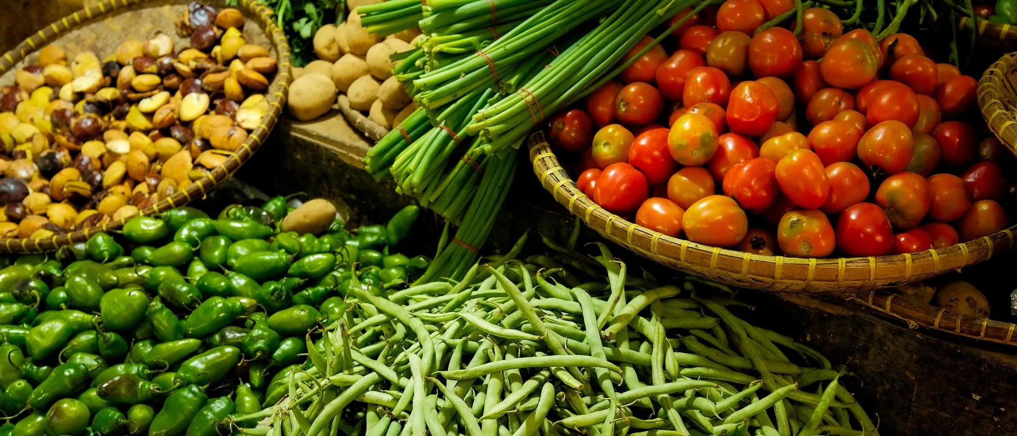 Heaps of fresh vegetables laid out side by side on a market stall.