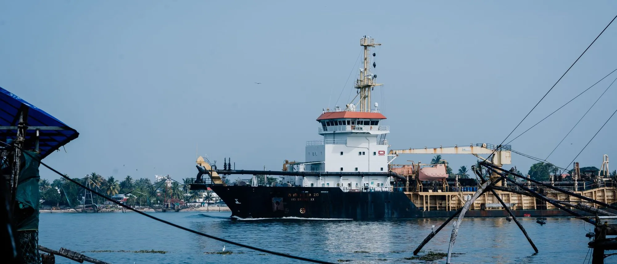 A cargo ship lies at anchor in Kochi harbour beyond the frames of the Chinese fishing nets.