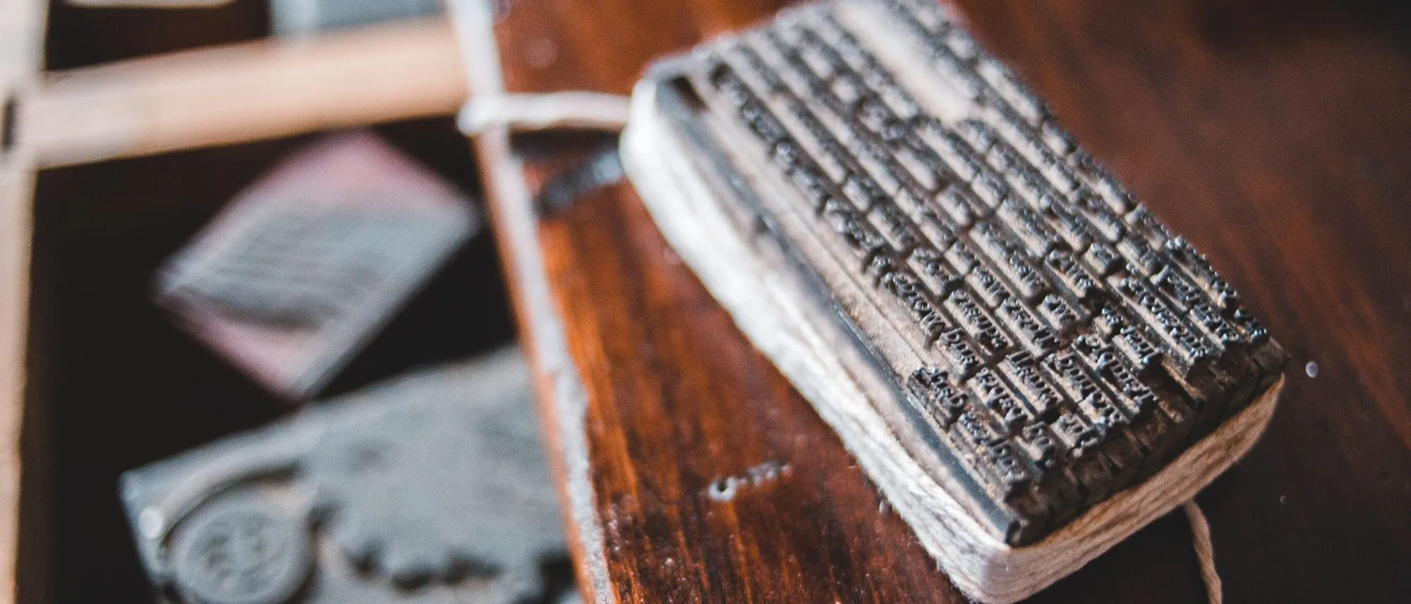 A block of set metal type tied with string on a wooden desk in a print workshop.