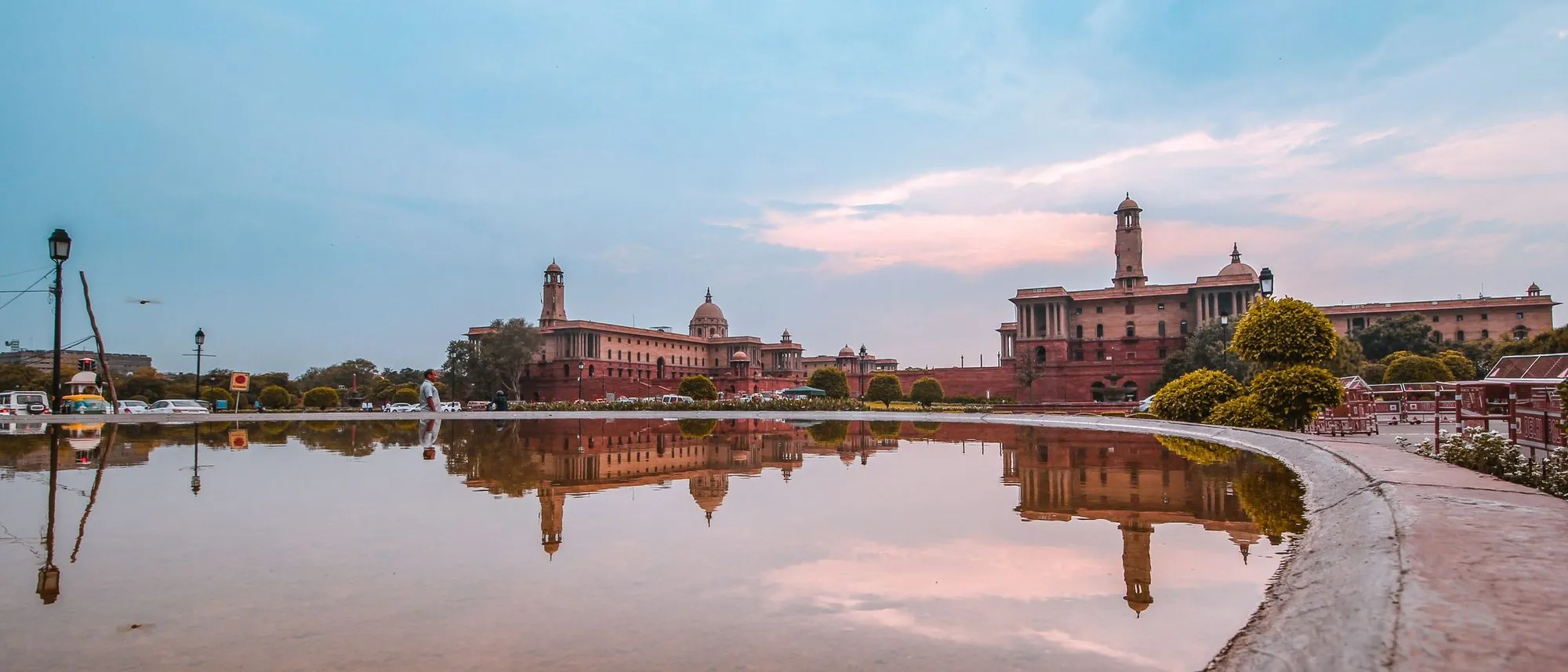 Rashtrapati Bhavan in New Delhi reflected in a still pond at sunset.