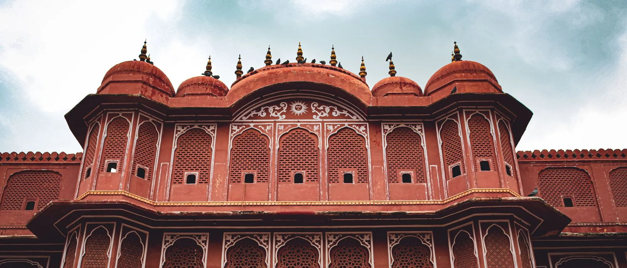 The carved red sandstone façade of an Indian palace with arched balconies.