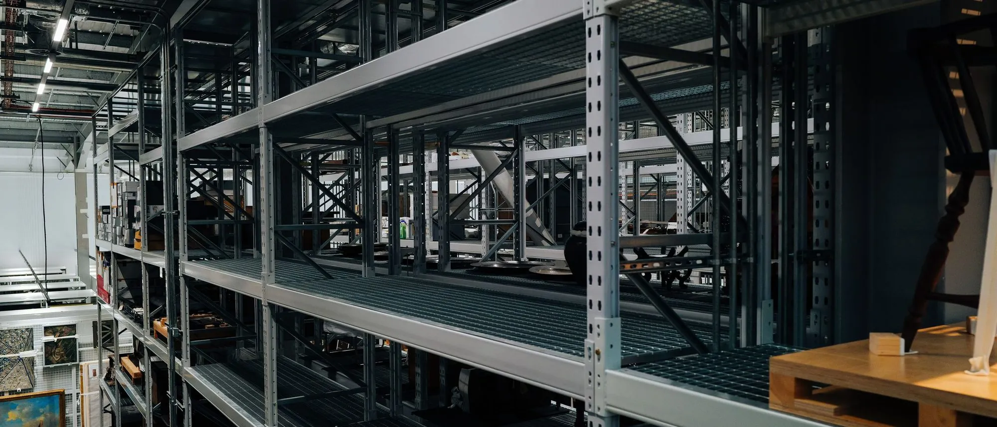 Empty metal storage racks in rows across a large industrial warehouse.
