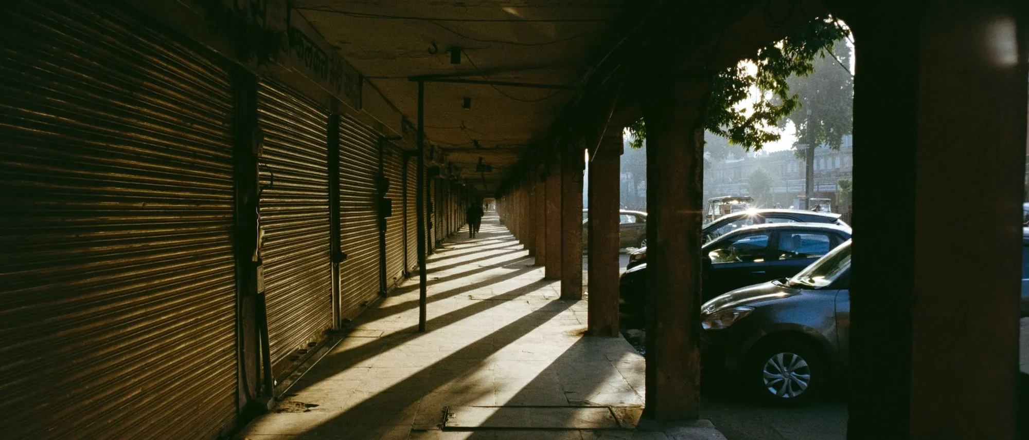 Early sunlight throws long shadows down a quiet market lane in Jaipur.