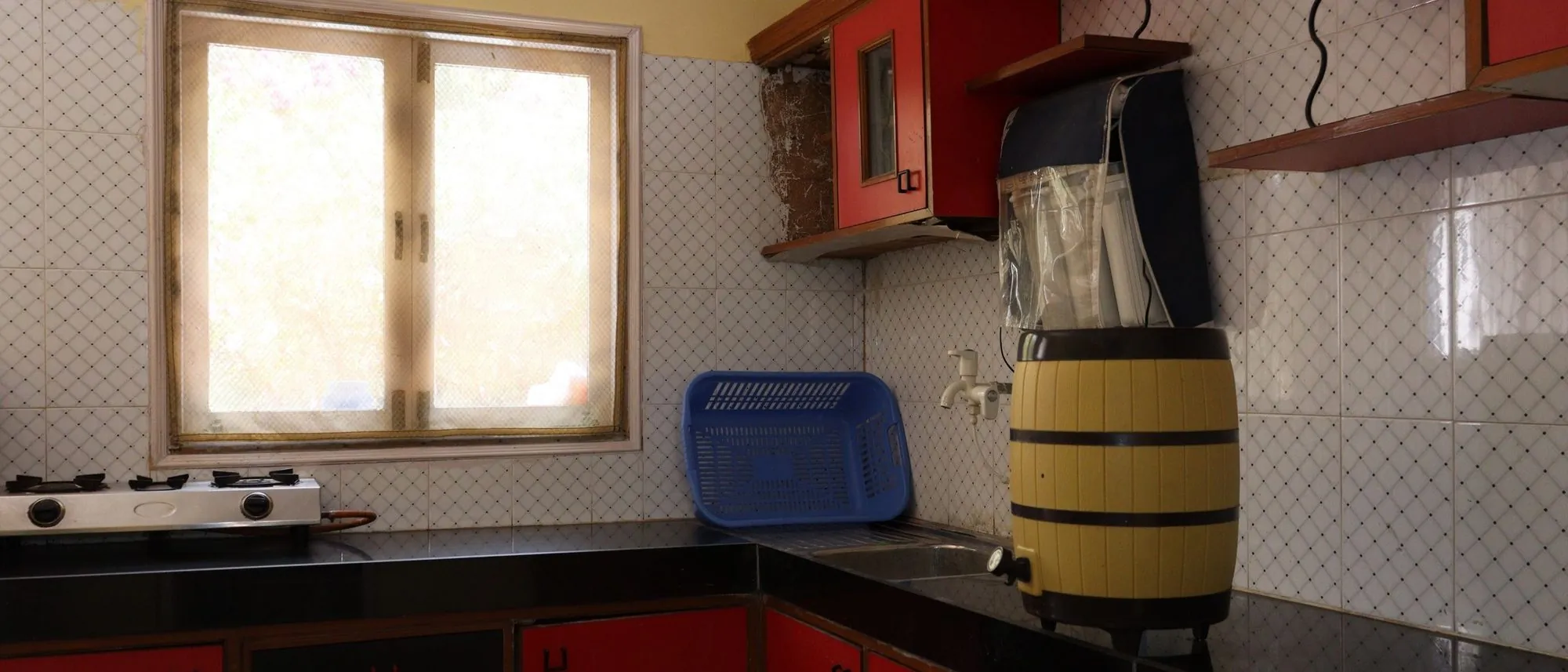 A home kitchen in Ahmedabad with red cabinets and window light on the counter