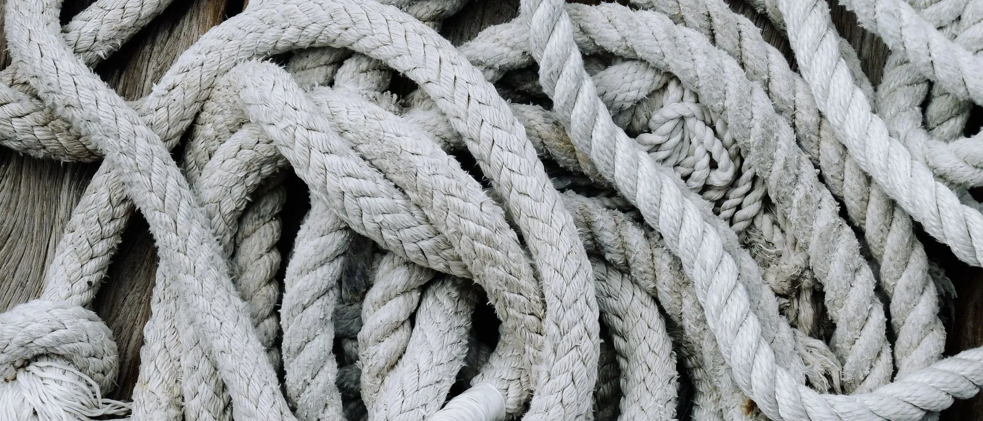 Coiled and tangled marine rope lies on a weathered wooden deck.