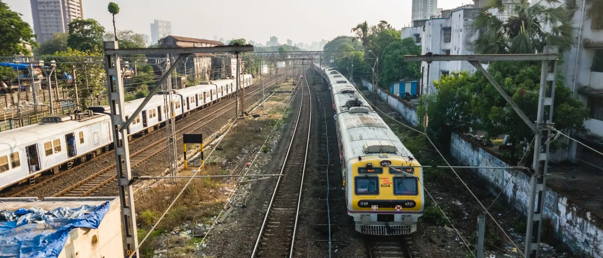 Trains on parallel tracks at a Mumbai railway station seen from above.