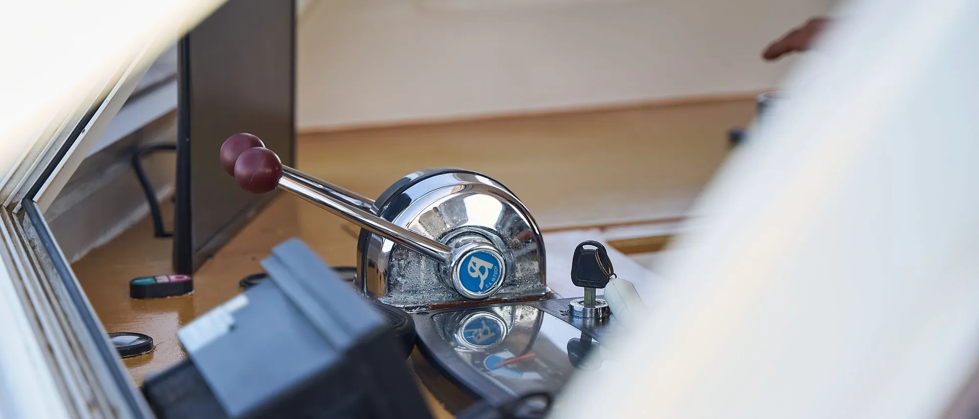 A row of polished metal control levers on a boat, with window light reflected in the steel.