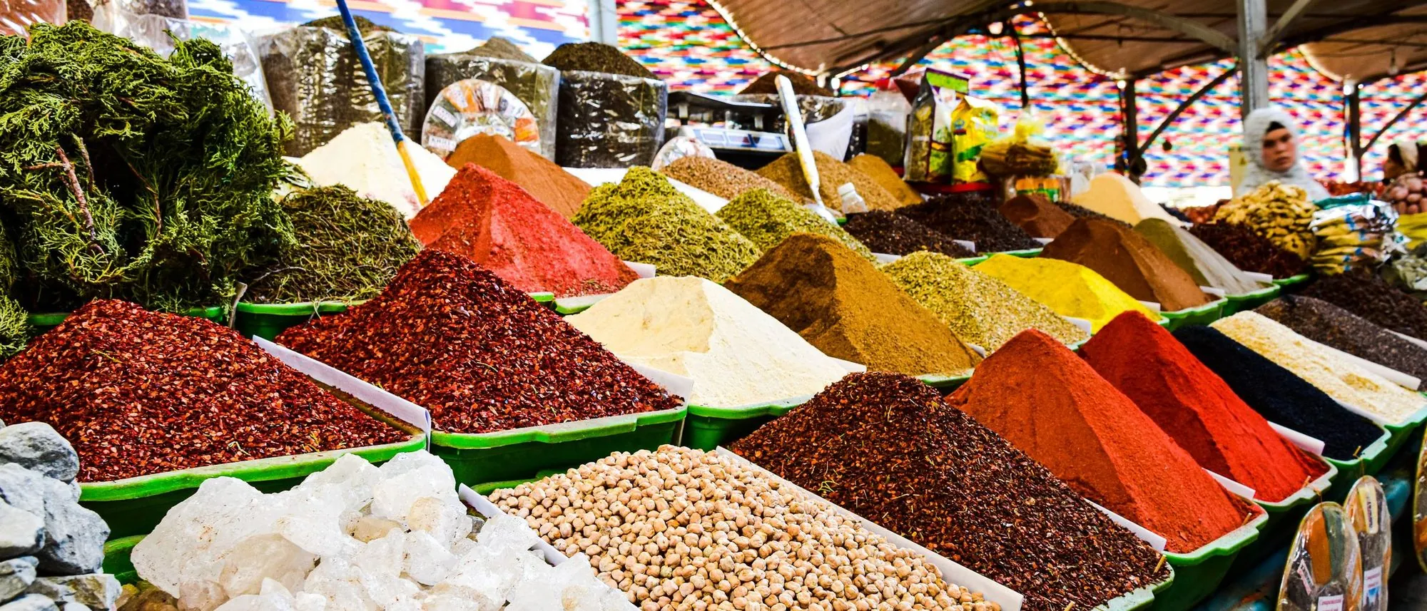 Mounds of ground spices in many colours are heaped in rows on a bazaar stall.