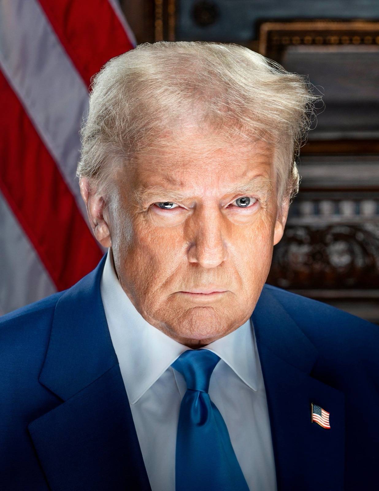 Donald Trump in his official presidential portrait of January 2025: a dark blue suit, white shirt, blue tie and a flag pin, an American flag behind him, looking straight into the camera unsmiling