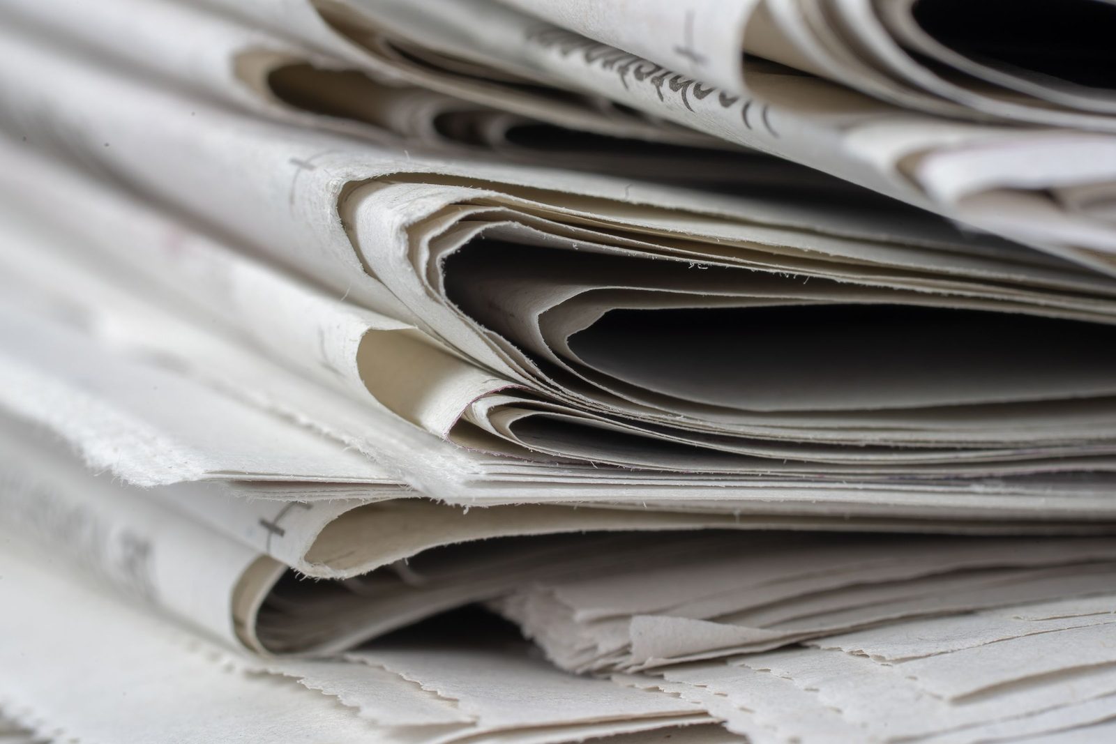 A close-up of folded newspapers stacked on top of one another