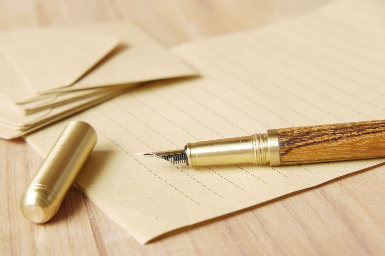 A gold fountain pen resting on lined paper.