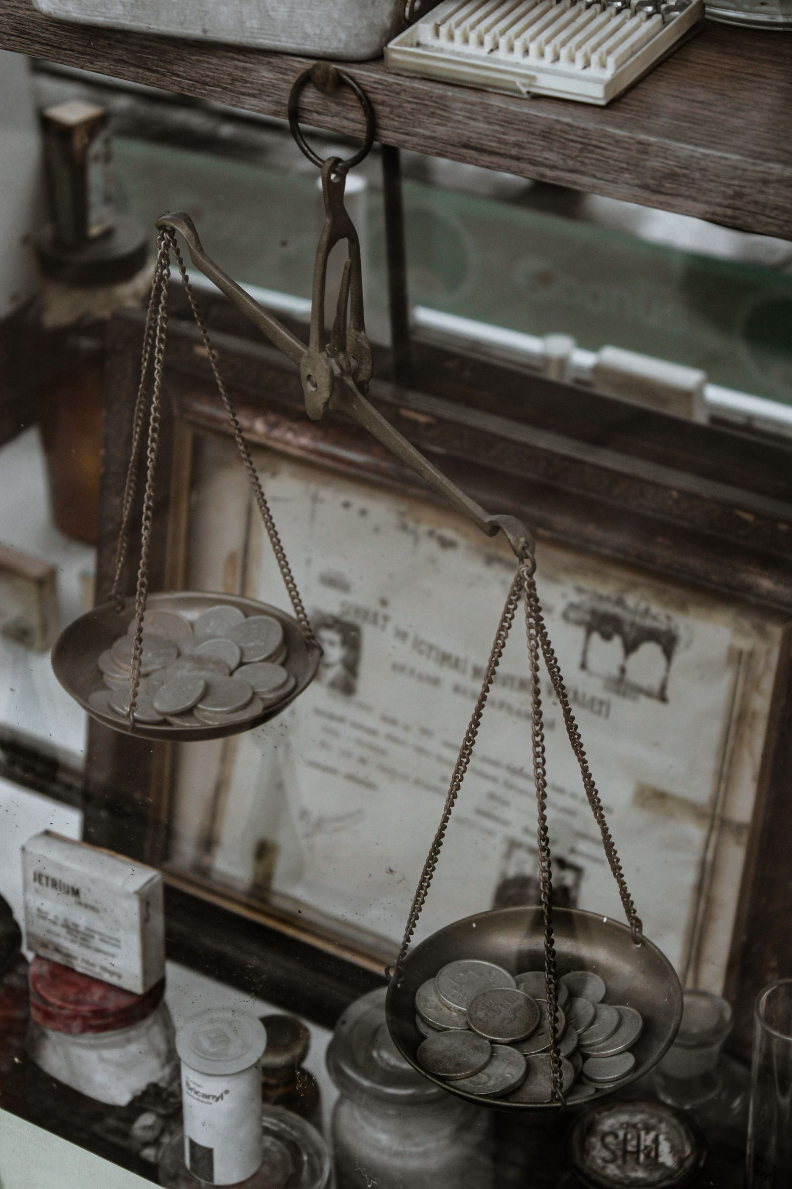 Silver coins resting on the pan of an antique weighing scale in a collection room.