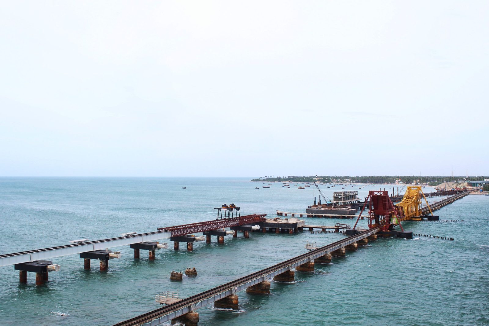 The Pamban railway bridge runs across blue sea between Rameswaram island and the mainland, seen from above.