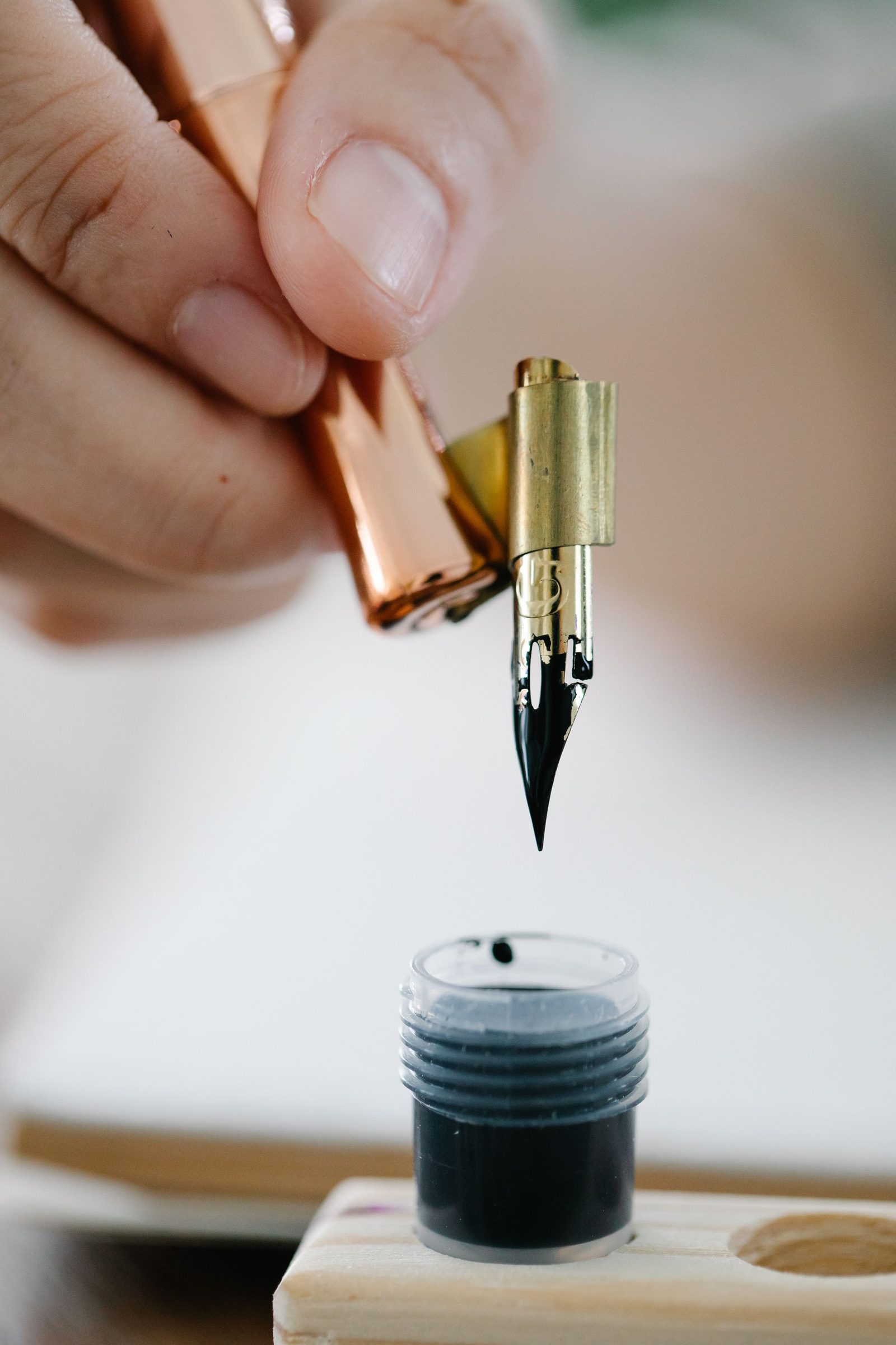 A fountain pen being dipped into a bottle of ink.