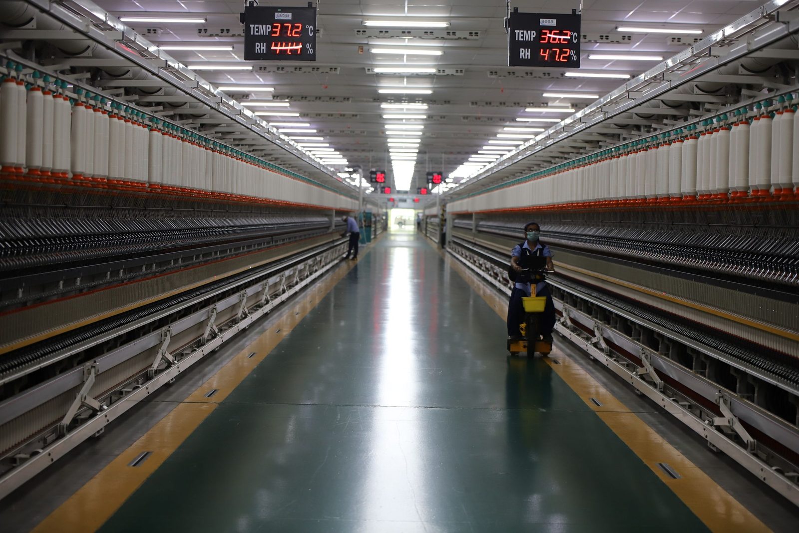 A long hall of spinning machinery in an Indian textile factory.