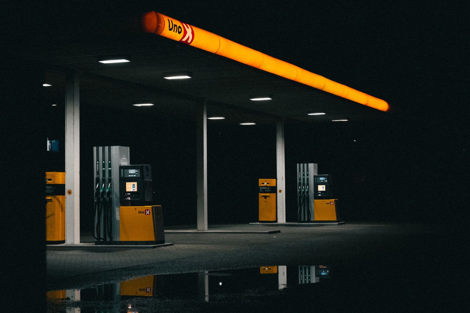 An empty petrol station at night lit by orange lights.