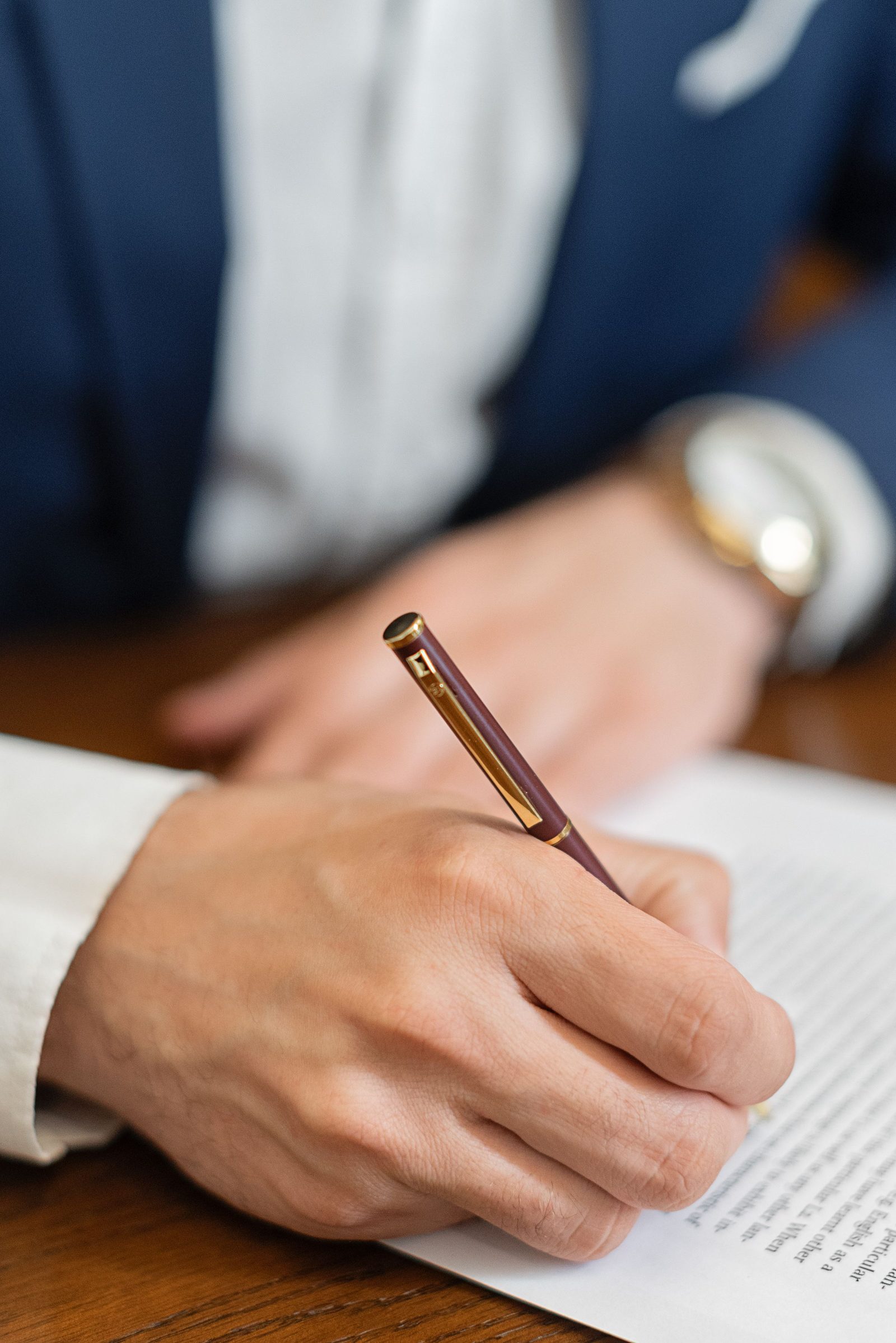A hand signing a contract with a fountain pen in close-up.