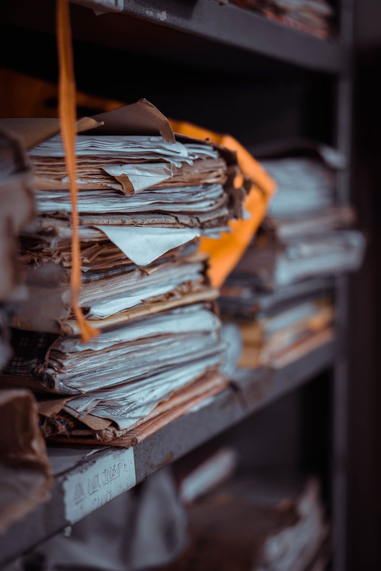 Stacks of old papers and registers piled on dusty shelves.