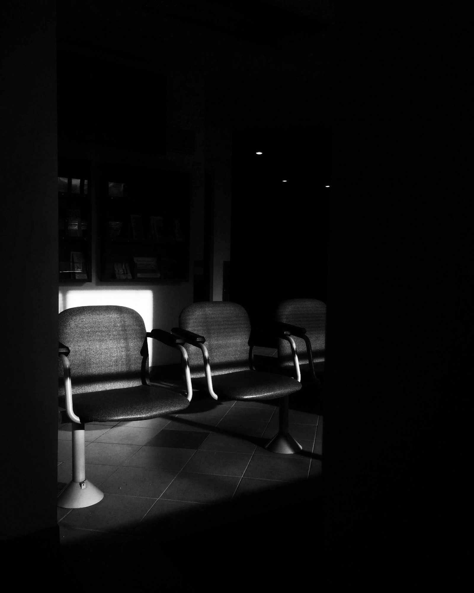 Empty chairs in a dim waiting area photographed in black and white.