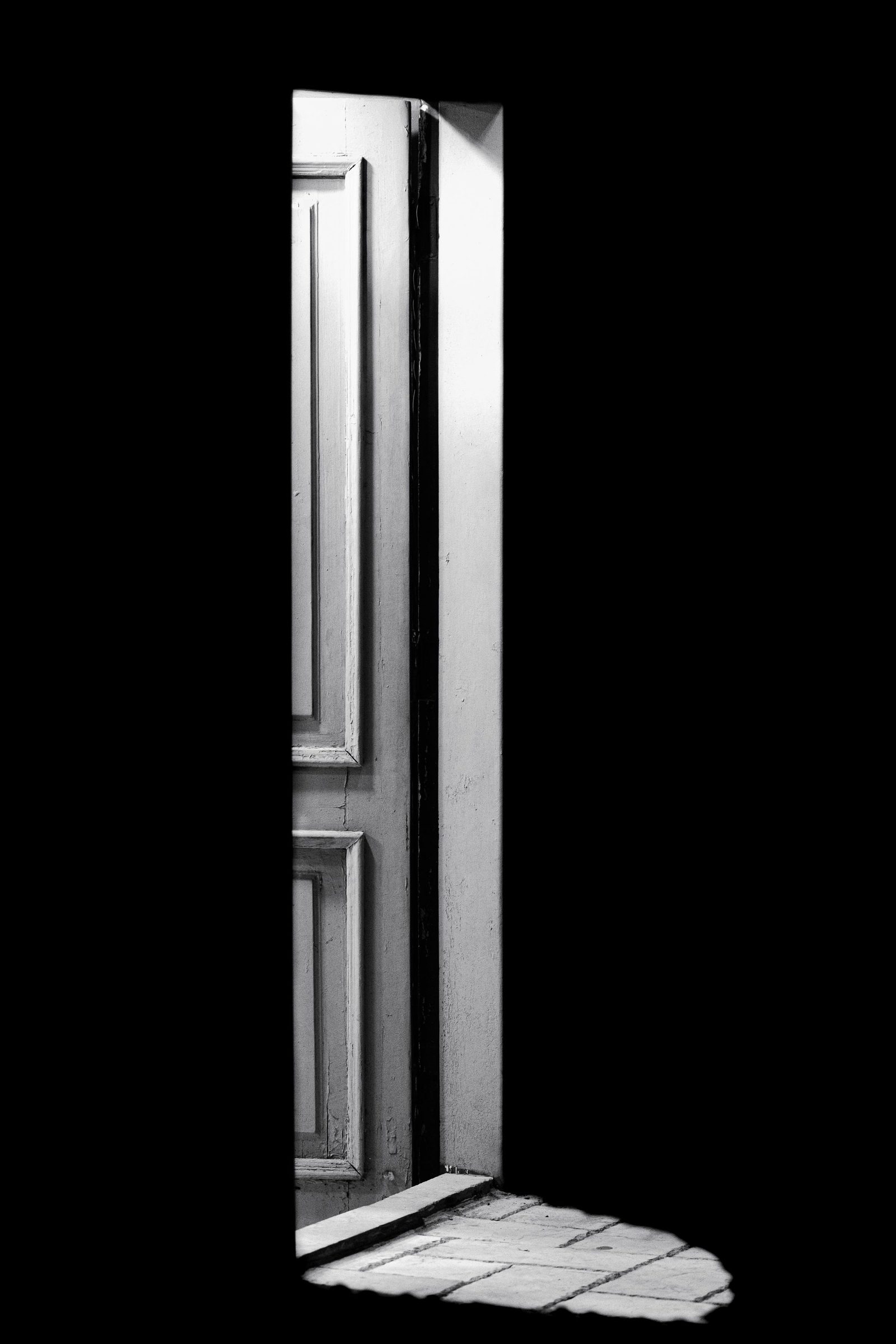 Light falls through an open door and throws a sharp shadow across the floor.