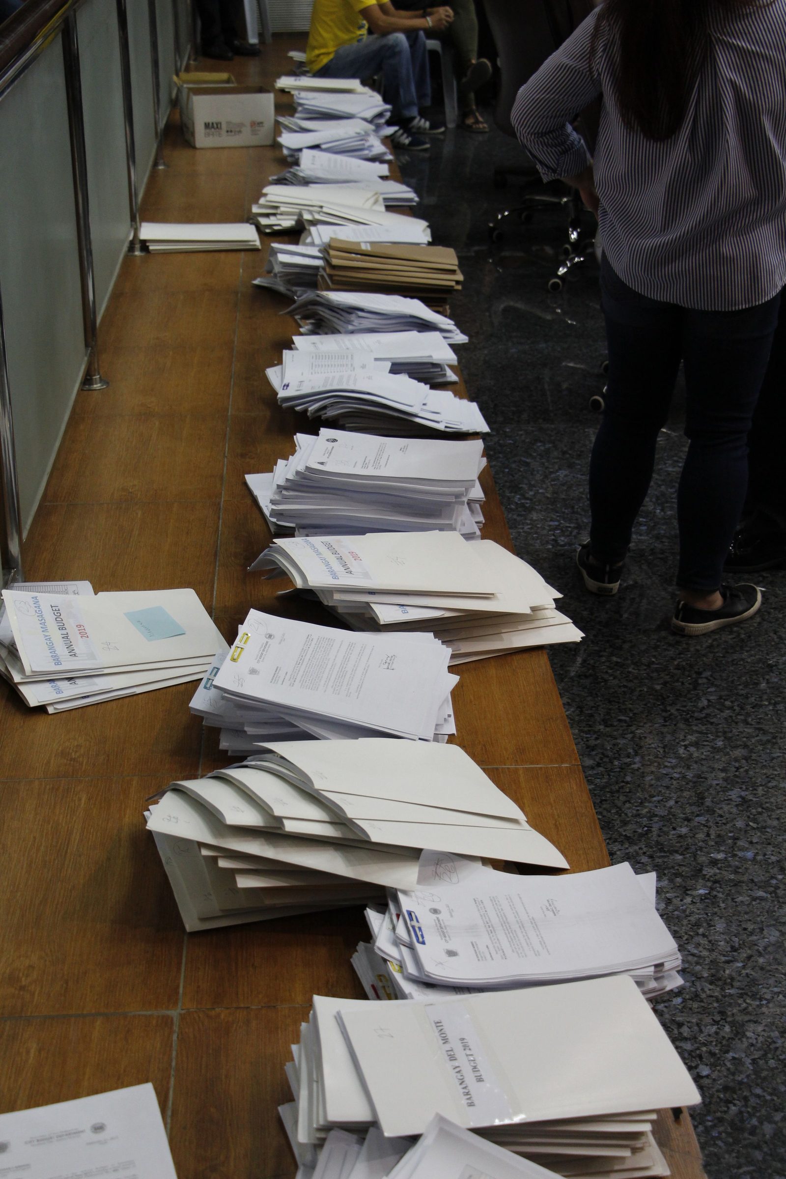 Neat stacks of white paper are arranged on a wooden desk.