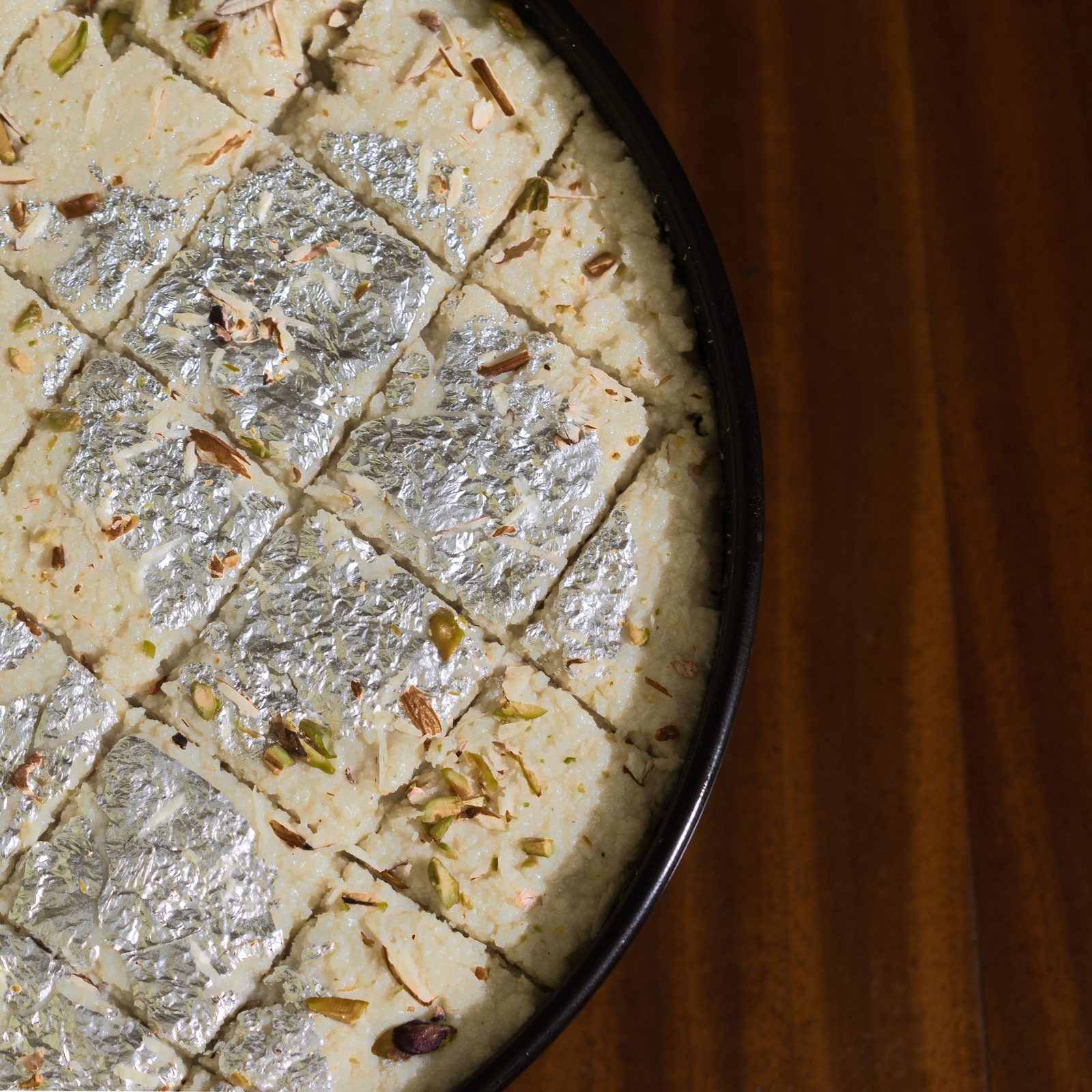 Sliced kalakand sweets covered in silver foil.