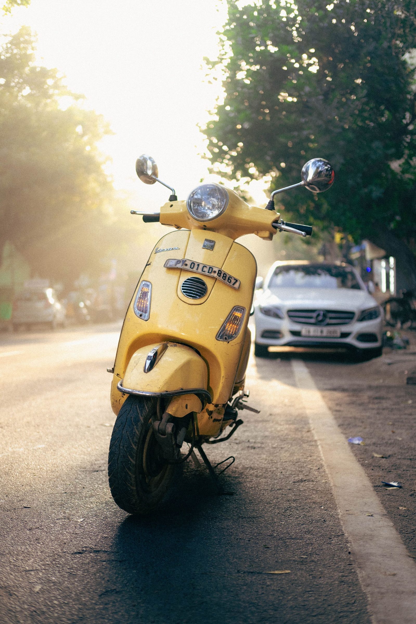 A yellow scooter parked on a quiet Puducherry street at sunrise.