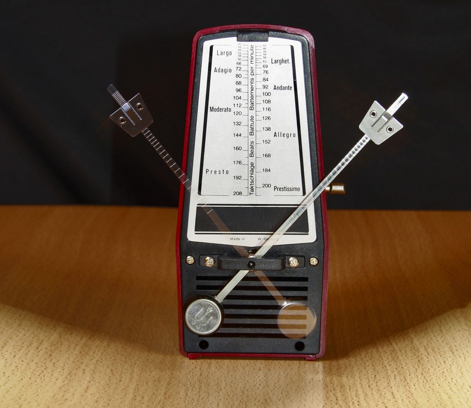 A vintage mechanical metronome standing on a wooden table.