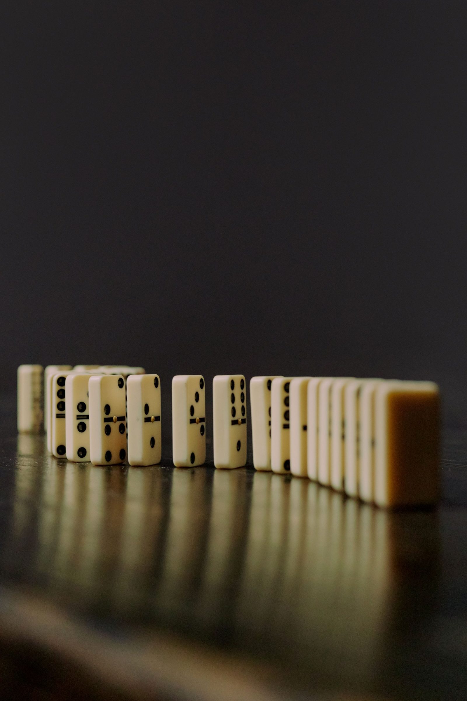 A row of domino blocks stands on a reflective surface.