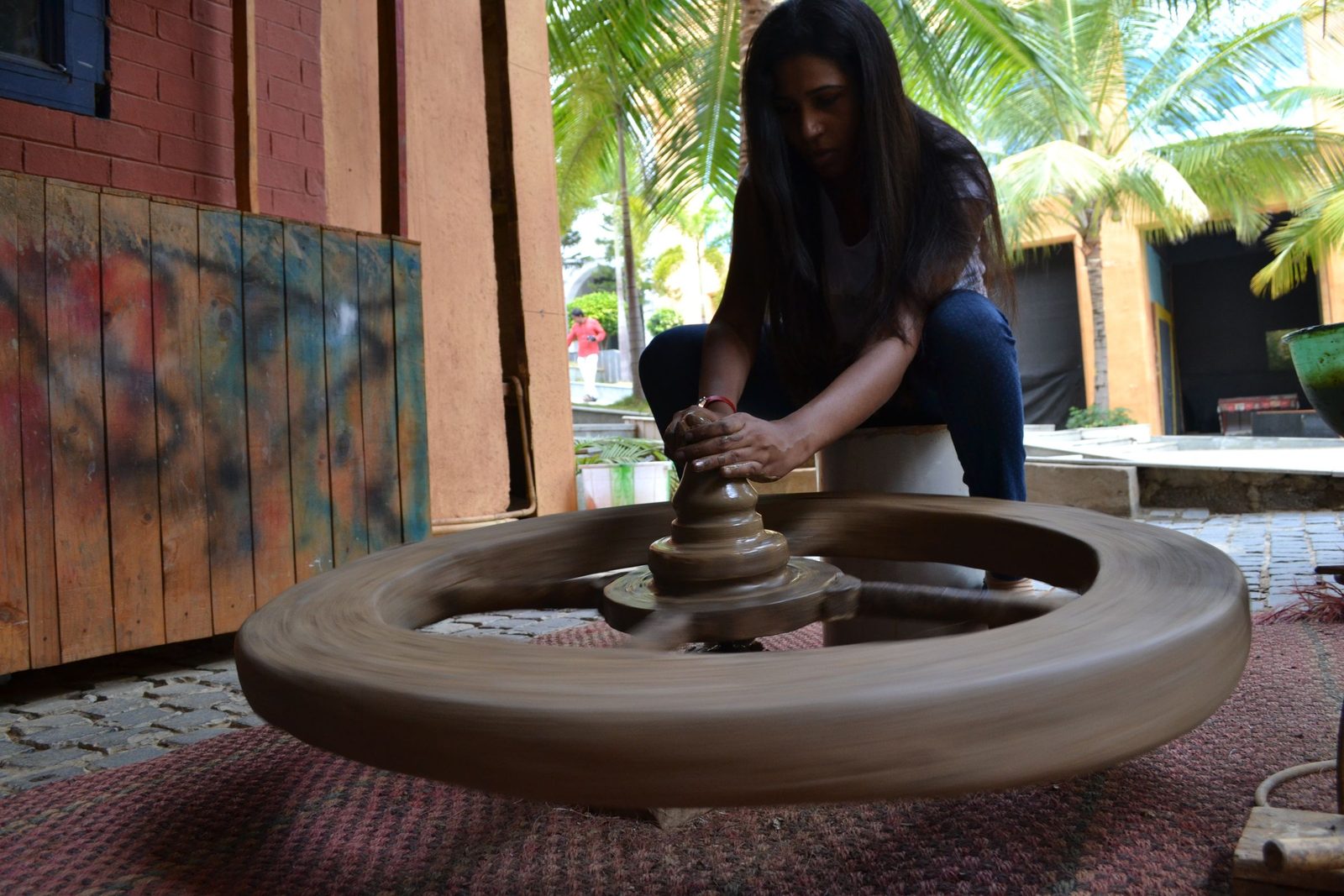 A woman shapes clay on a potter’s wheel outdoors in Bengaluru.