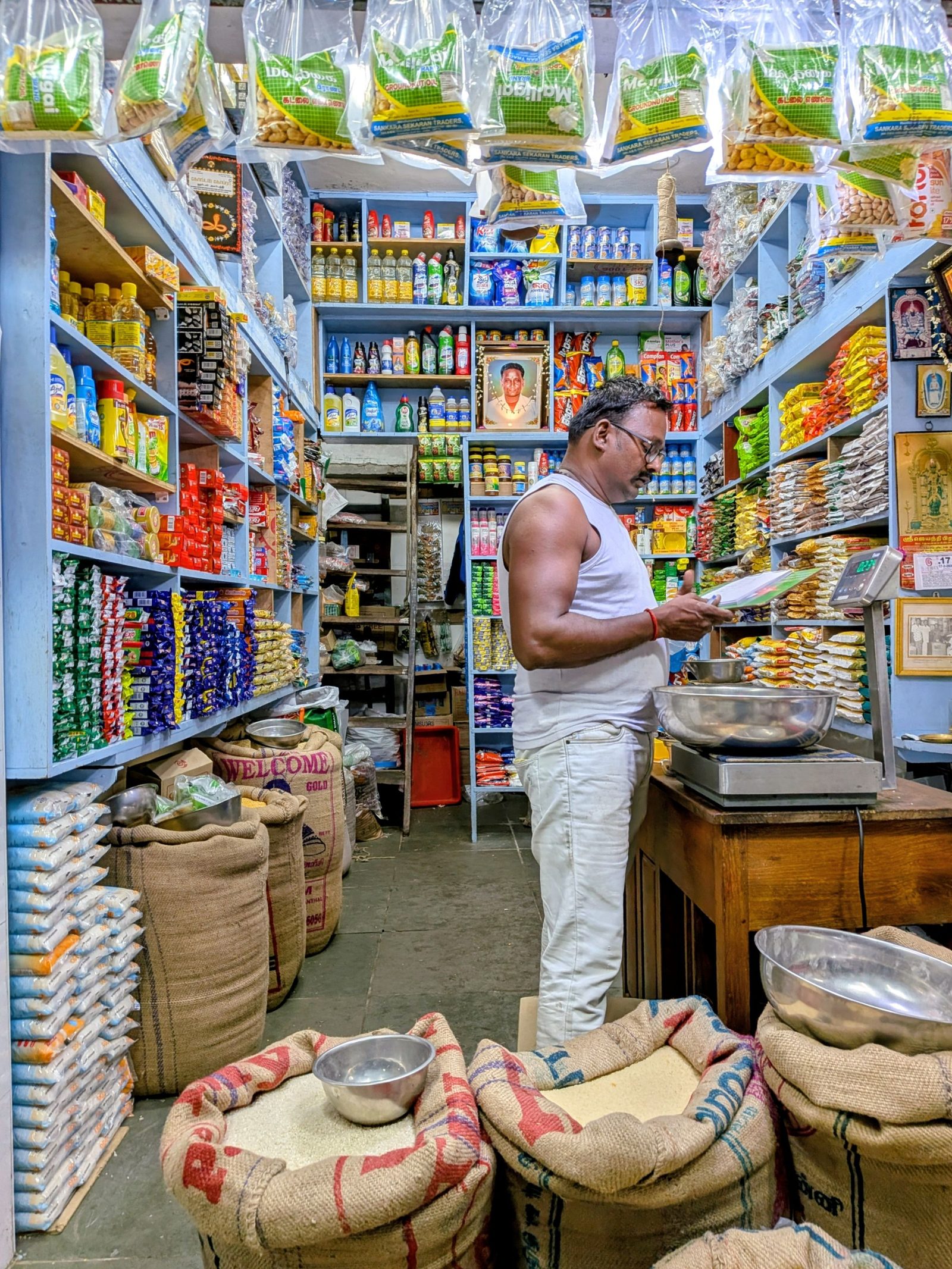 A shopkeeper checks stock inside a crowded Indian grocery store.