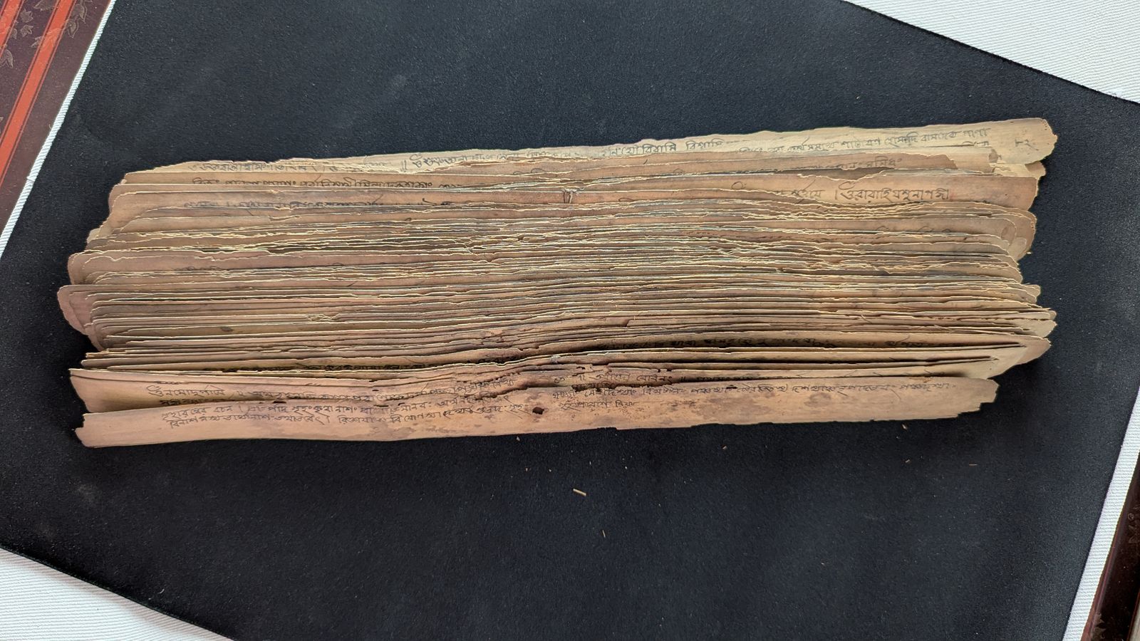 A bundle of inscribed palm-leaf manuscript pages on a dark surface