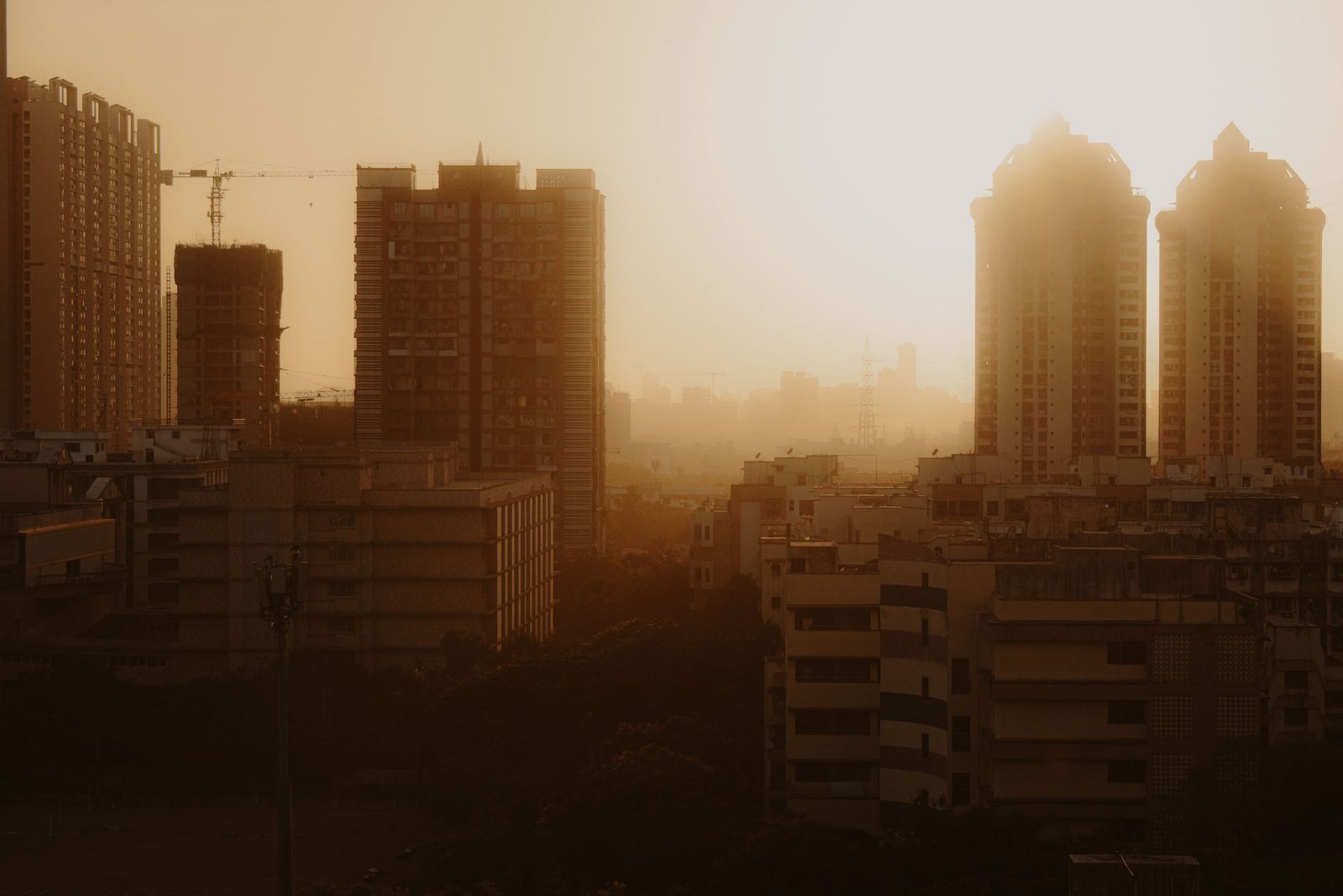 High-rise buildings in Mumbai stand in silhouette against a warm sunset.