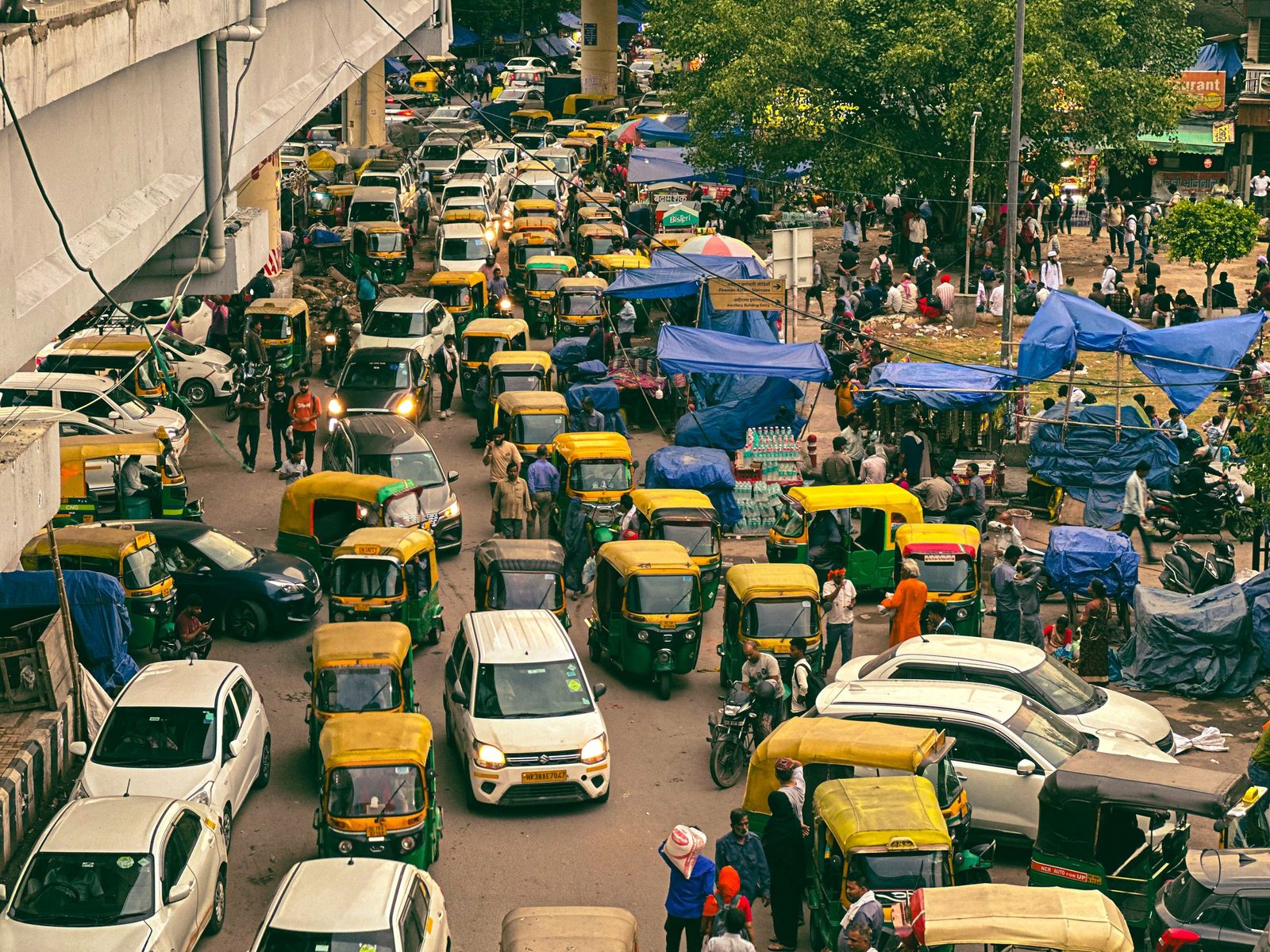 Seen from above a New Delhi market street is packed with auto-rickshaws, cars and pedestrians.