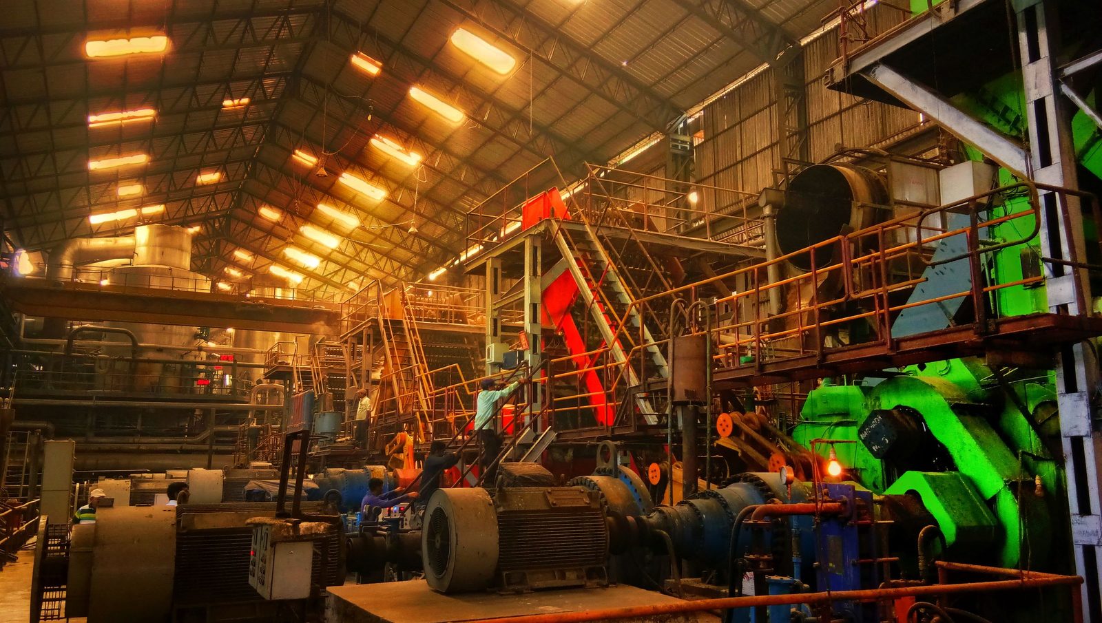 The interior of a busy factory in Ahmedabad, with rows of machinery under a high roof.