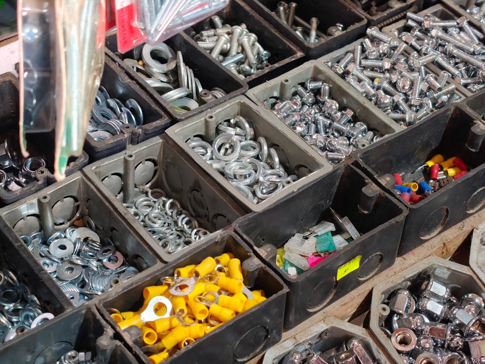 Nuts, bolts and washers sorted into black storage bins.