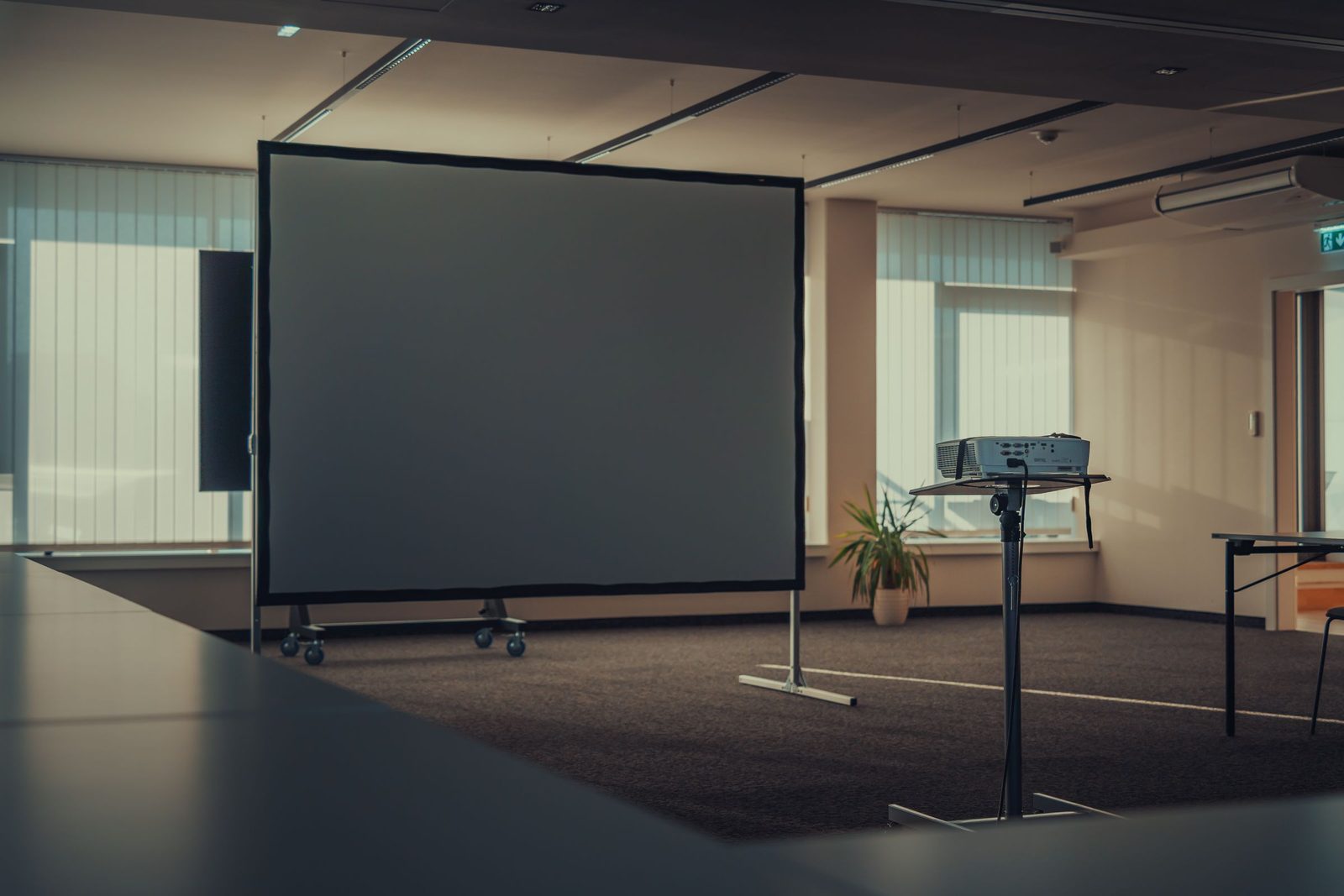 An empty modern office with a projector and a blank screen.