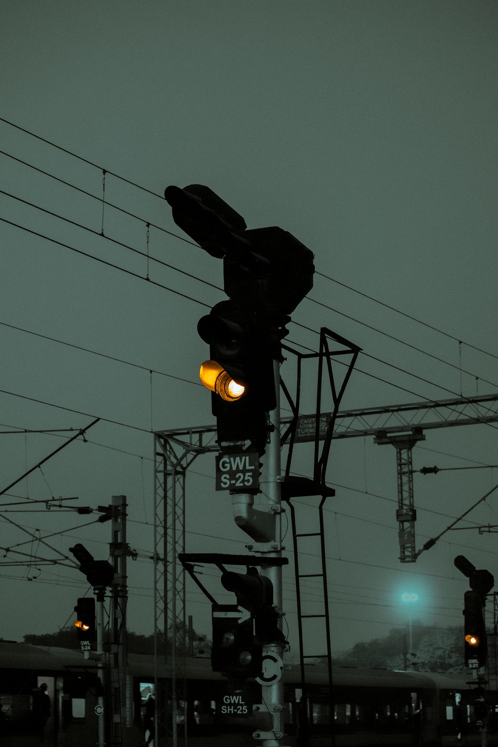 Railway signals glowing yellow at Gwalior station in the evening.