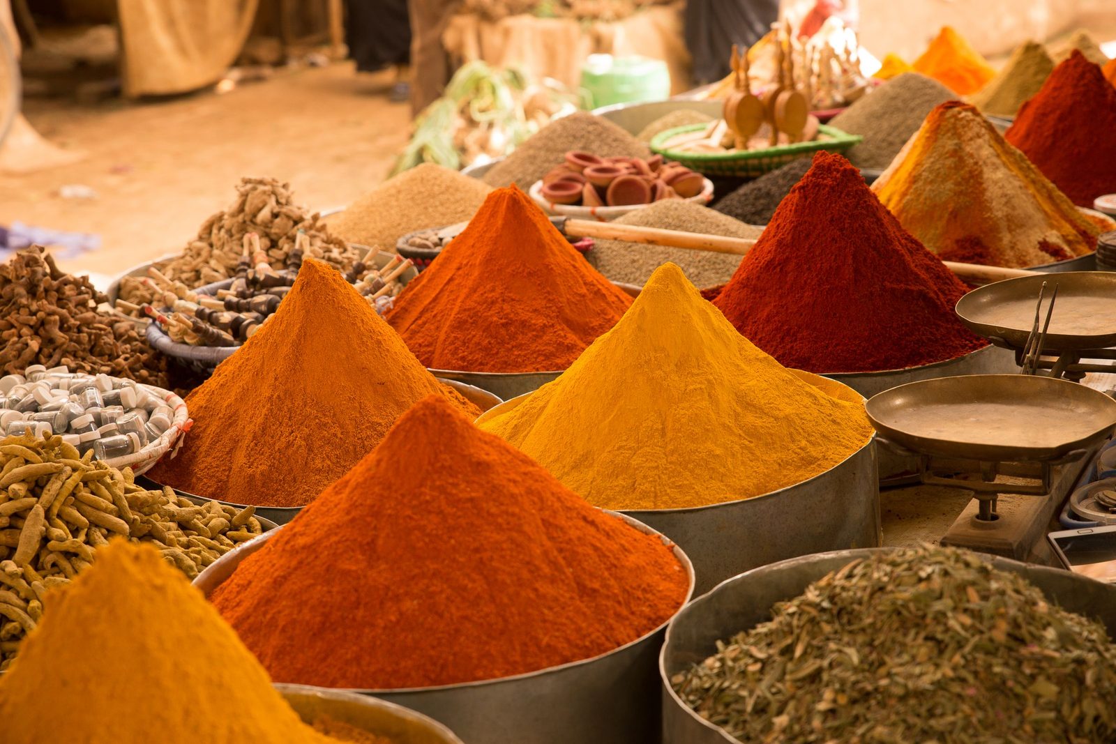 Mounds of orange and red spices are heaped on a street market stall.