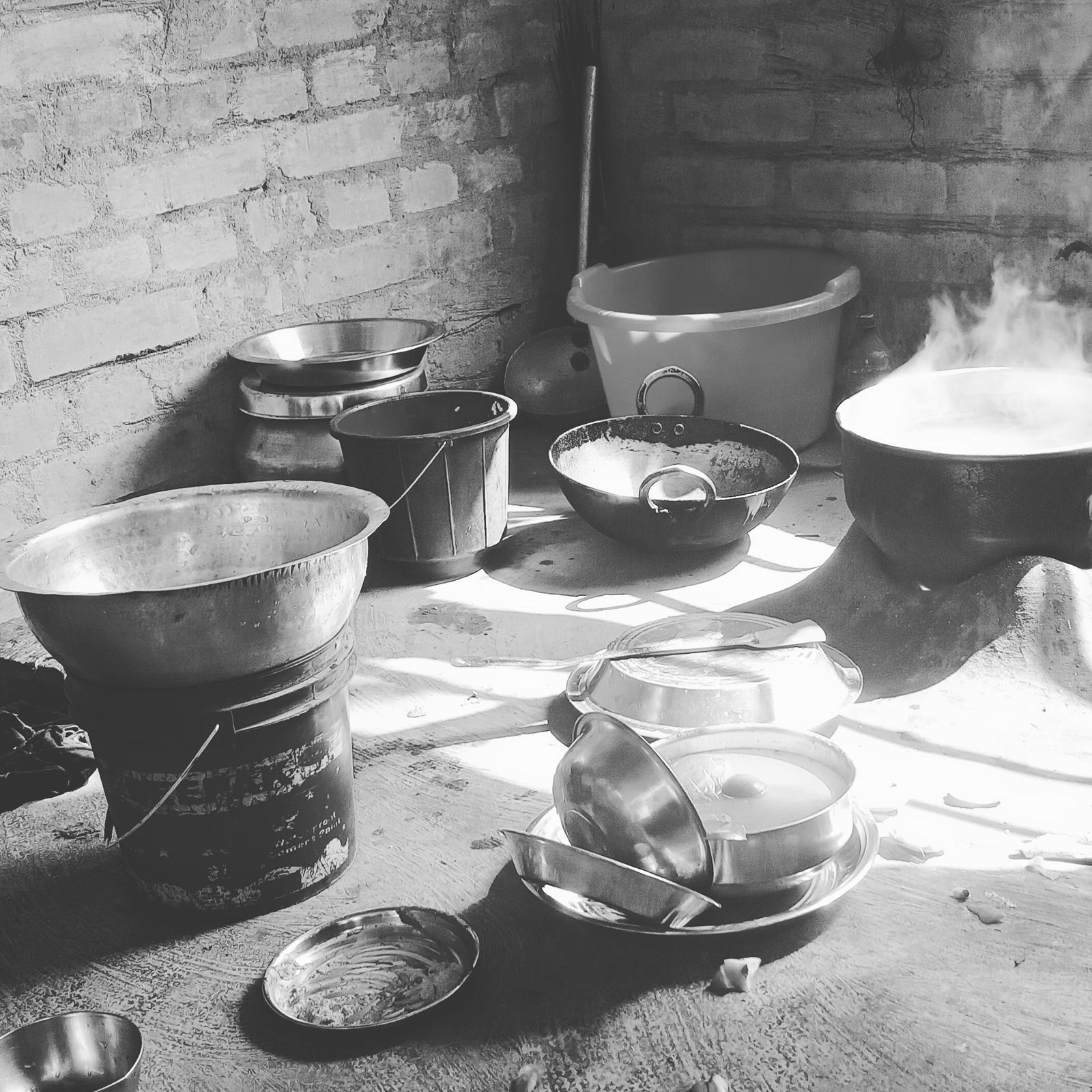 Cooking pots and utensils fill a small Indian kitchen in black and white.