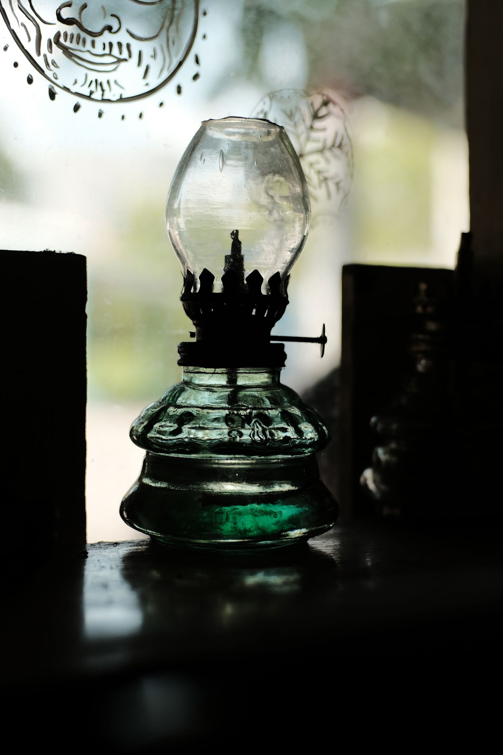 A kerosene lamp burns beside a window and lights the room.