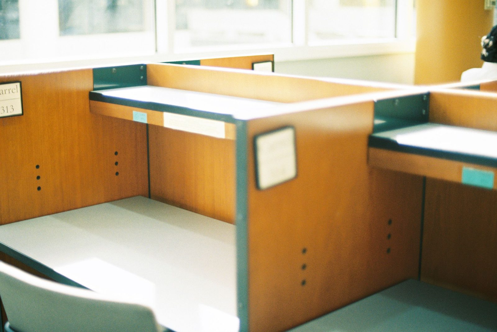 Empty wooden desks stand in a sunlit office beside a window.