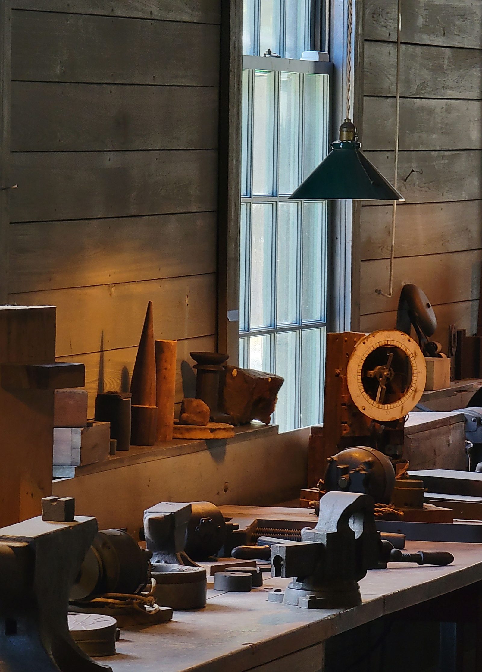 Vintage hand tools on a wooden workbench lit by a window.